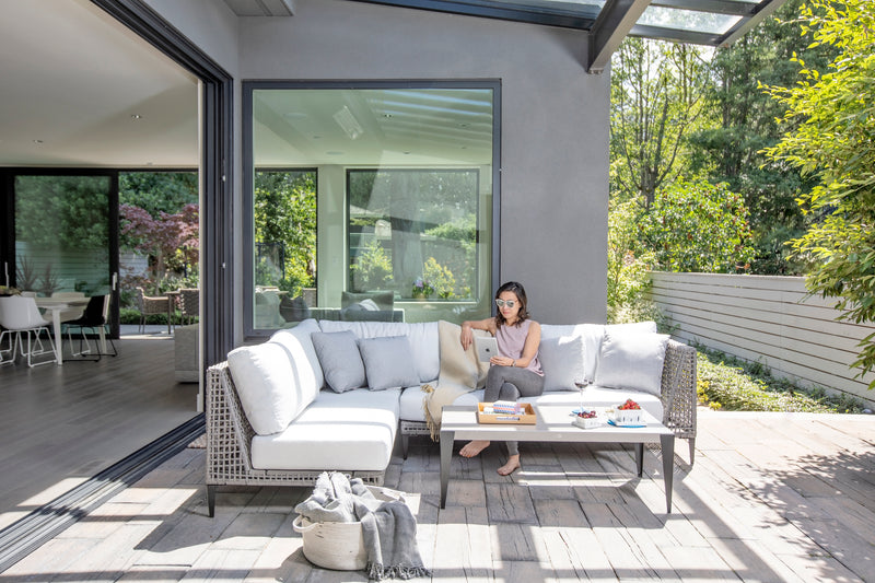 A woman sitting on an outdoor sofa reading an iPad